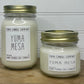 Large 16oz mason jar white soy candle with gold lid shown with a smaller 8oz soy candle. Both have white labels with grey text reading Yuma Candle Company Yuma Mesa
